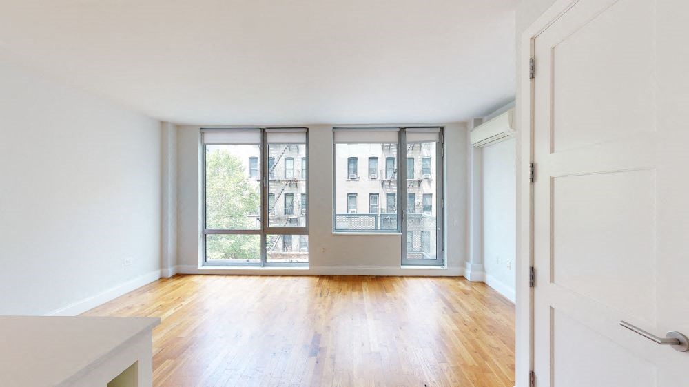 A room with a wooden floor and a large window with a view of a city.