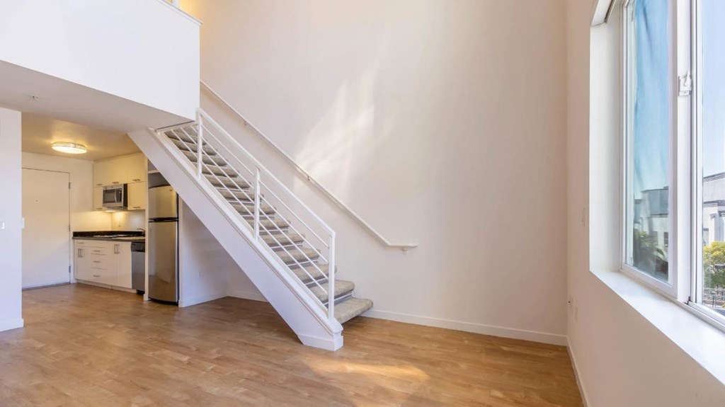 A white staircase with a wooden floor and a window on the side.