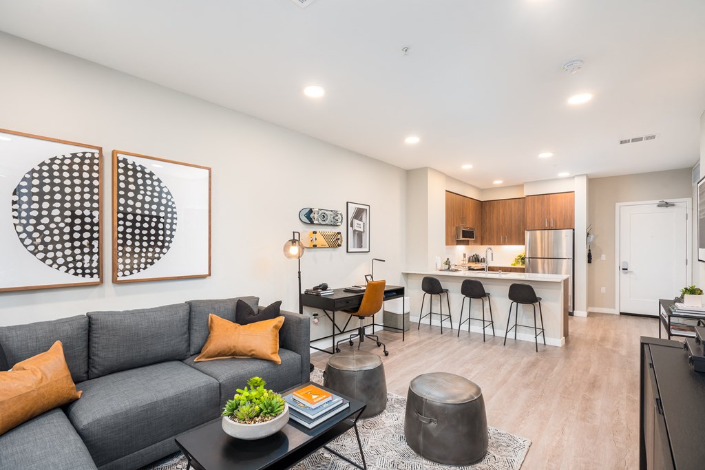 a living room with a gray couch and a kitchen with a bar