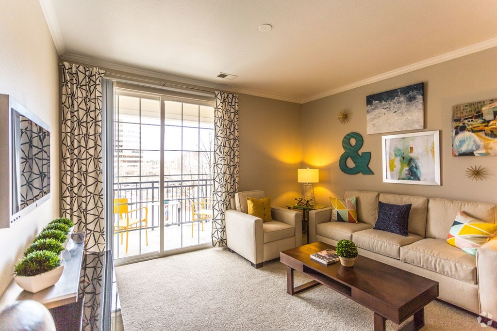 A living room with a sofa, a table, and a window with a view of the outside. at The Viridian Apartments, Greenwood Village, CO
