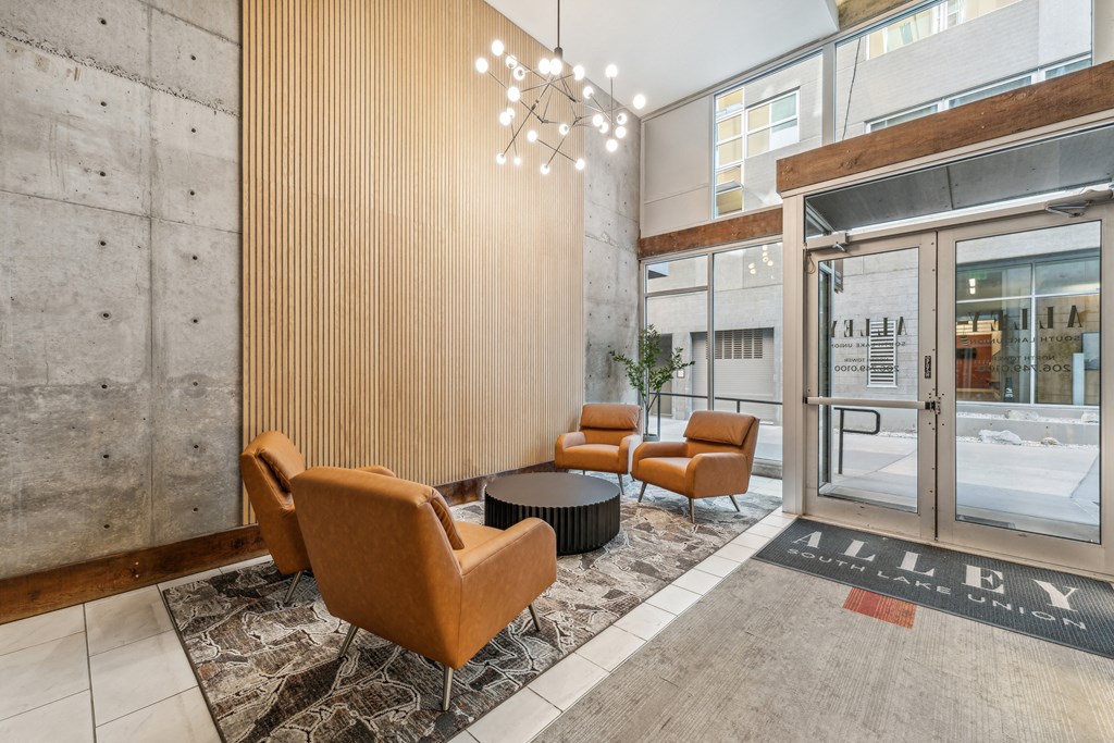 a lobby with chairs and a table in front of a glass door