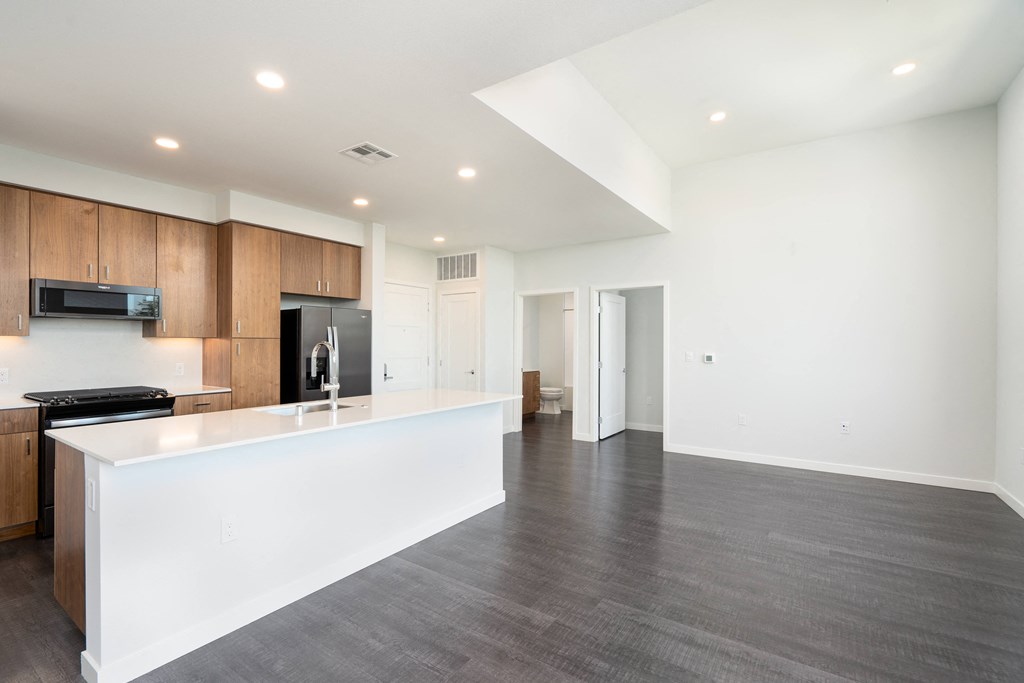 a kitchen with a white counter top and a large empty living room