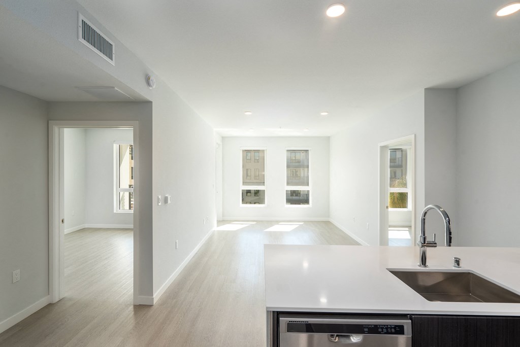 a kitchen and living room with white walls and wood floors