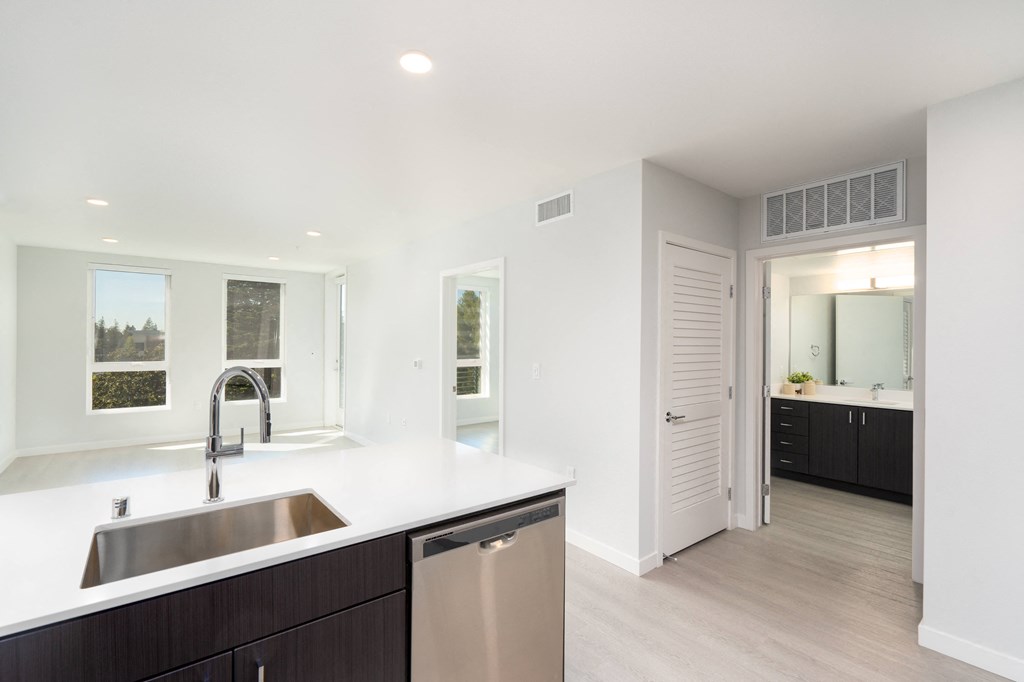 a white kitchen with a stainless steel sink and counter top