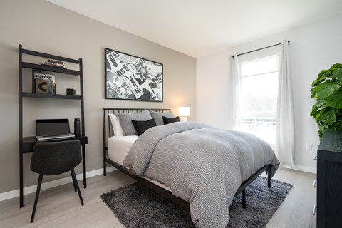 a bedroom with a bed and a desk and a window