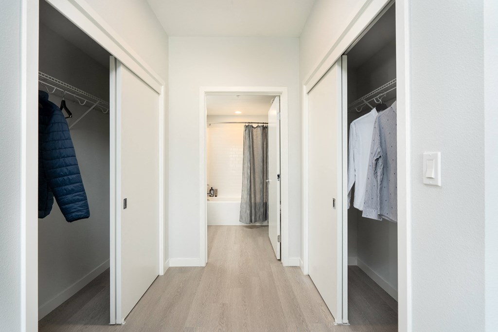 a walk in closet with a mirrored closet door and a hallway with mirrored closets