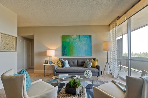 a living room with a couch and chairs and a large painting on the wall