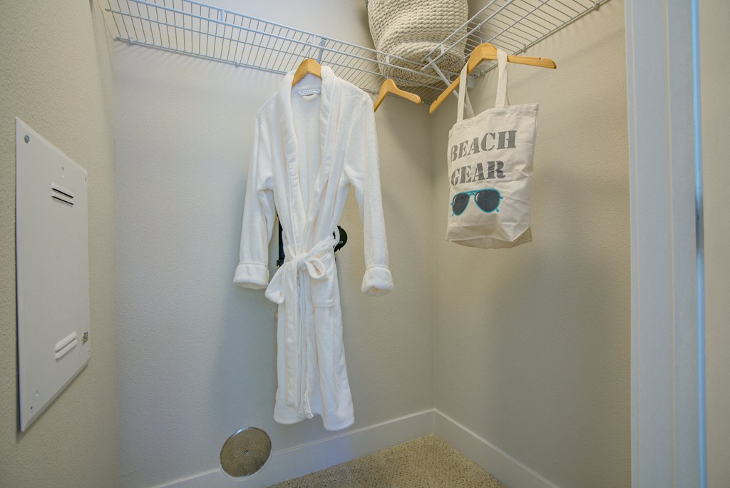 a white robe and a bag hanging on a rack in a closet