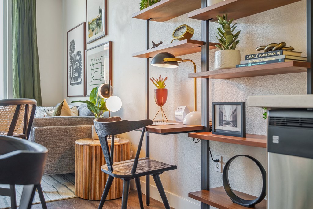 a living room with shelves and a desk with a chair and a couch