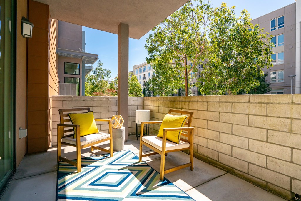 a patio with two yellow chairs and a wall with a tree