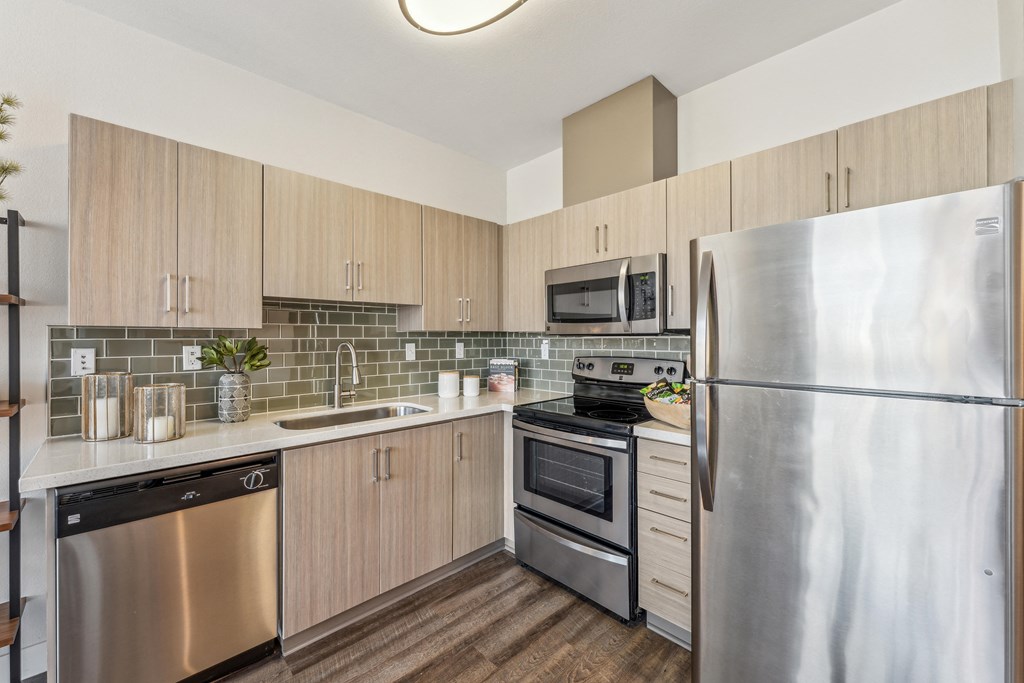 an apartment kitchen with stainless steel appliances and wooden cabinets