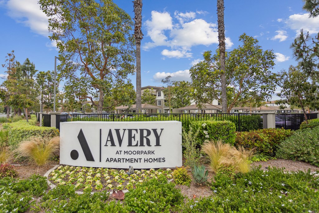 a yard with a sign for avery at woodland apartment homes