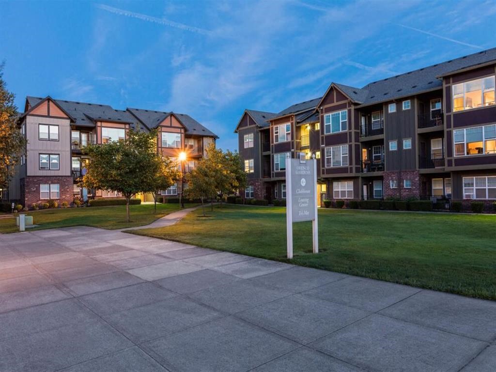 an apartment building at dusk with a sign in the grass