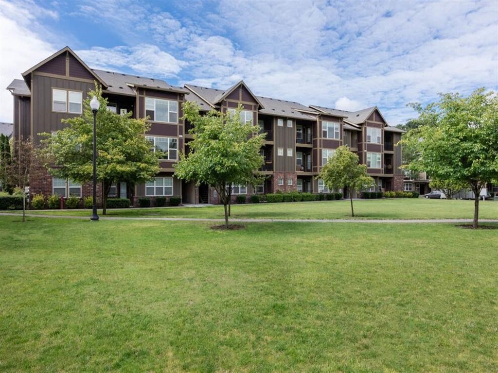 an apartment building with grass and trees in front of it