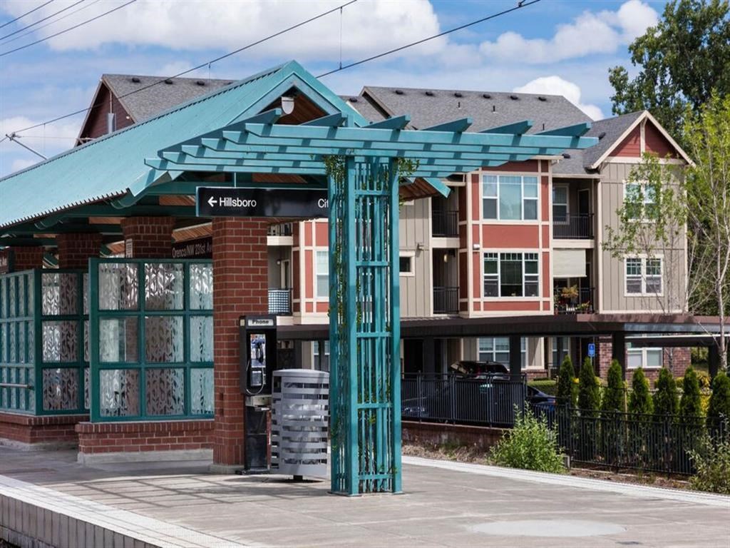 a train station with a green structure in front of a building