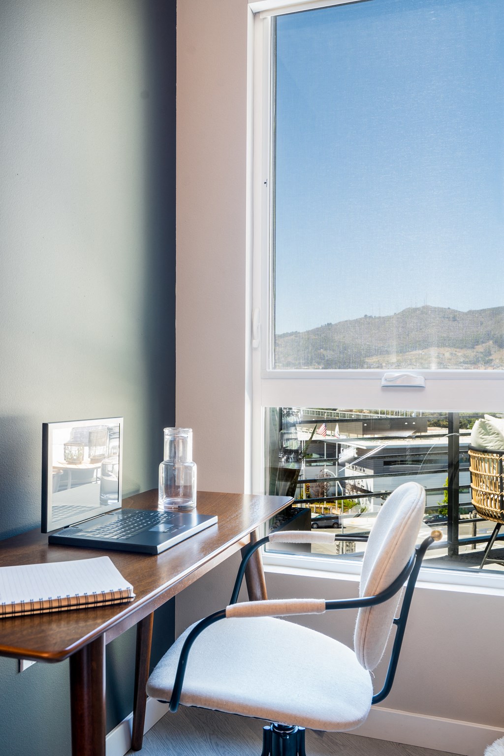 a desk with a laptop and a chair in front of a window