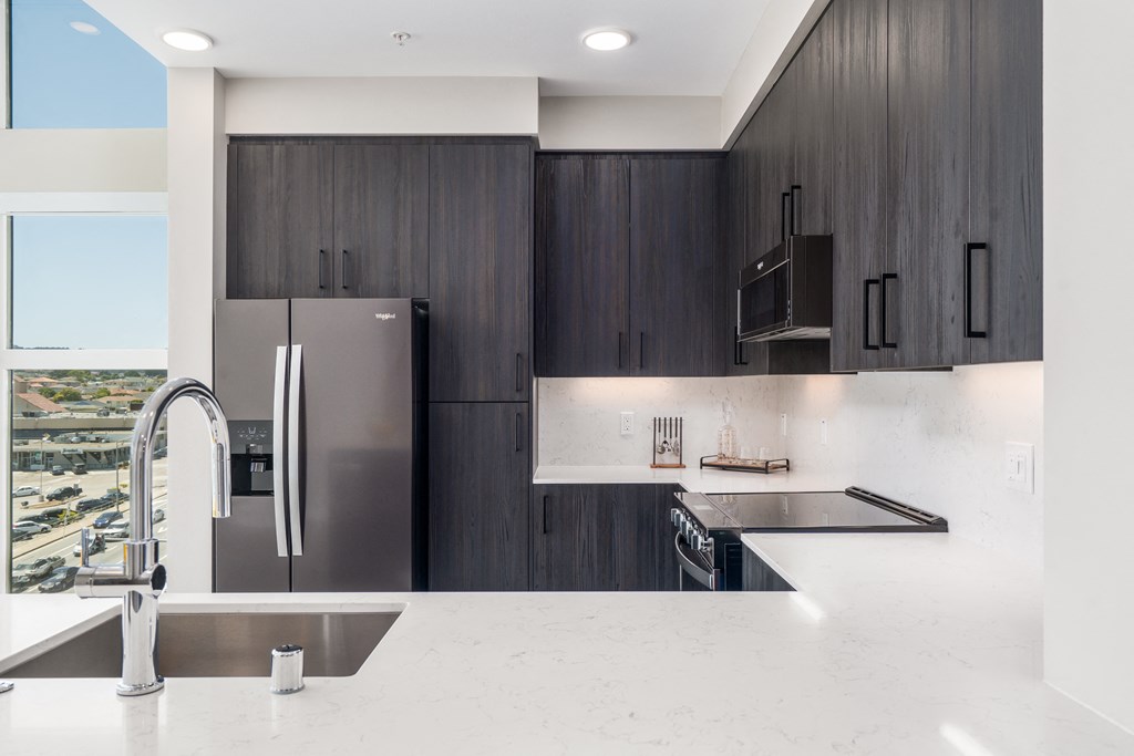 a modern kitchen with stainless steel appliances and white countertops