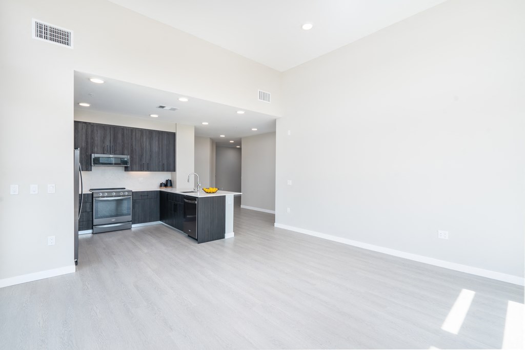 an empty living room and kitchen with white walls and wood flooring