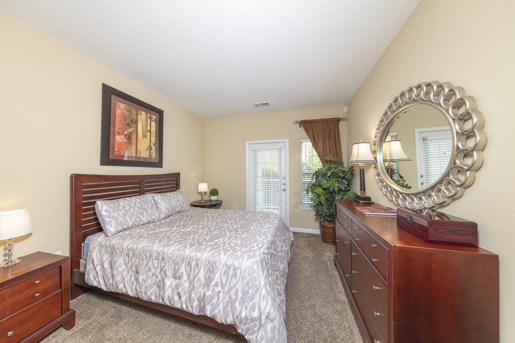 A bedroom with a bed, dresser, and mirror.