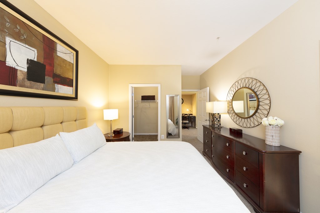 A bedroom with a large bed and a mirror on the wall.