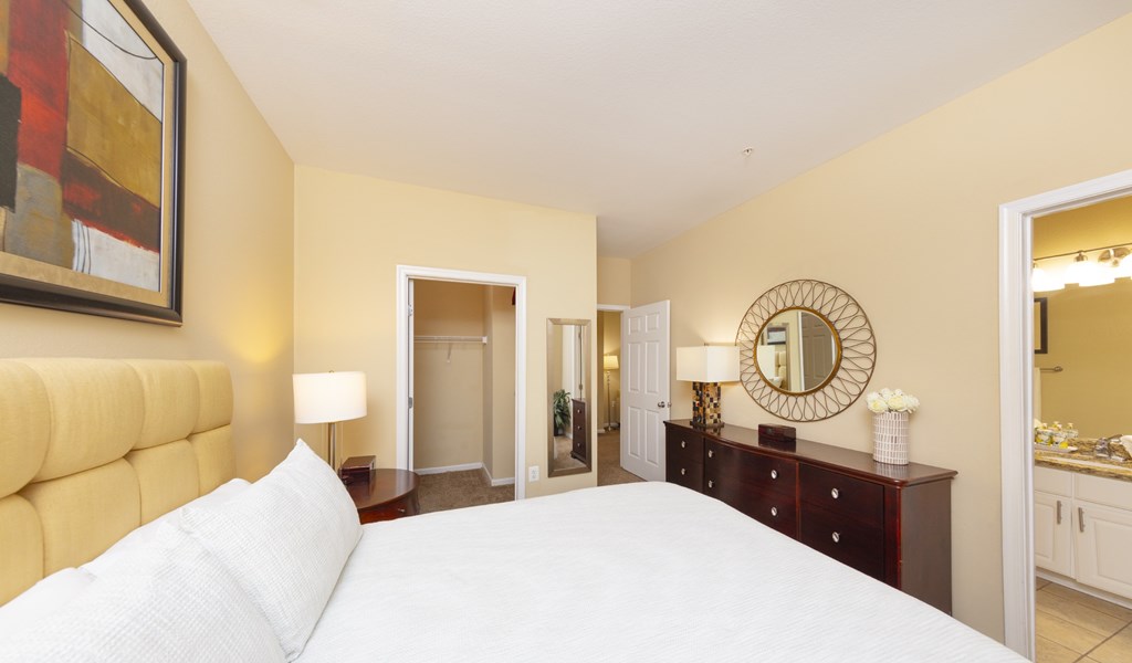 A bedroom with a large bed and a mirror on the wall.