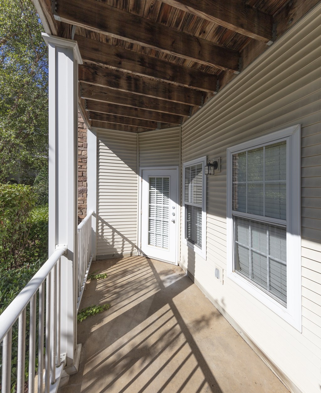 A sunny day at a white house with a wooden porch.