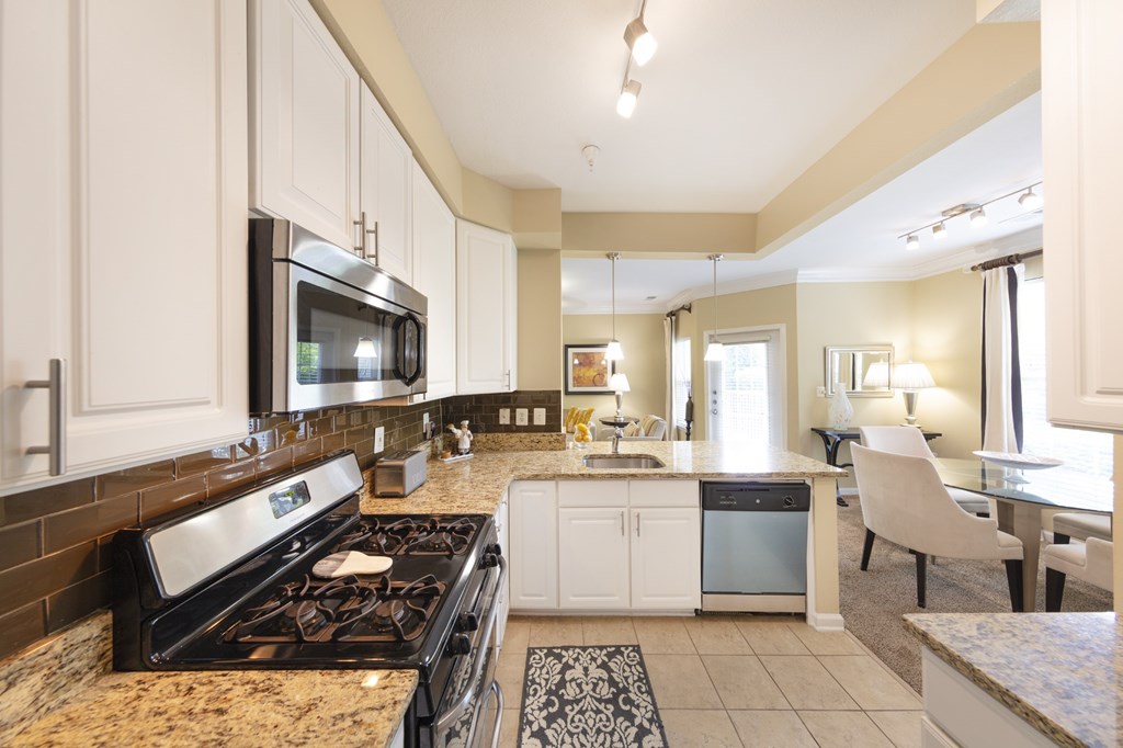 A modern kitchen with a black stove top oven and white cabinets.