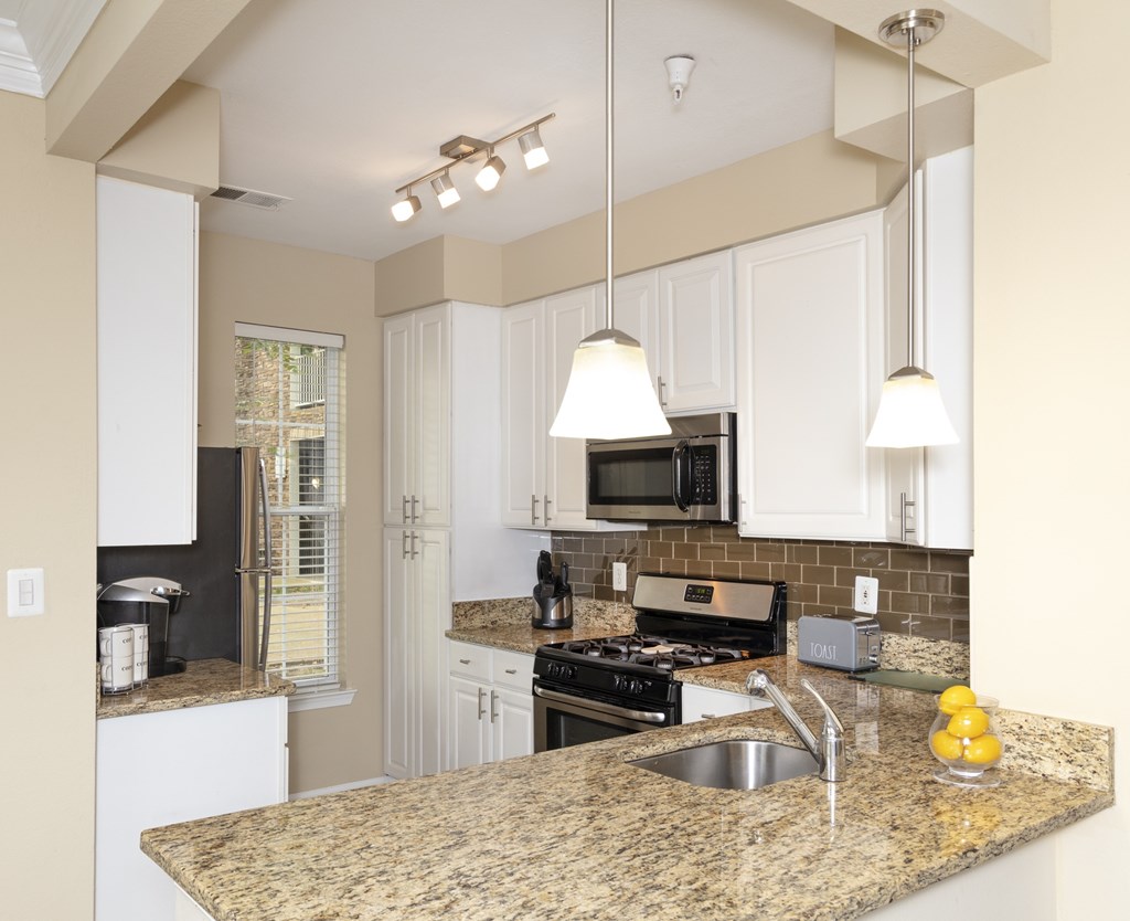 A kitchen with granite countertops and white cabinets.