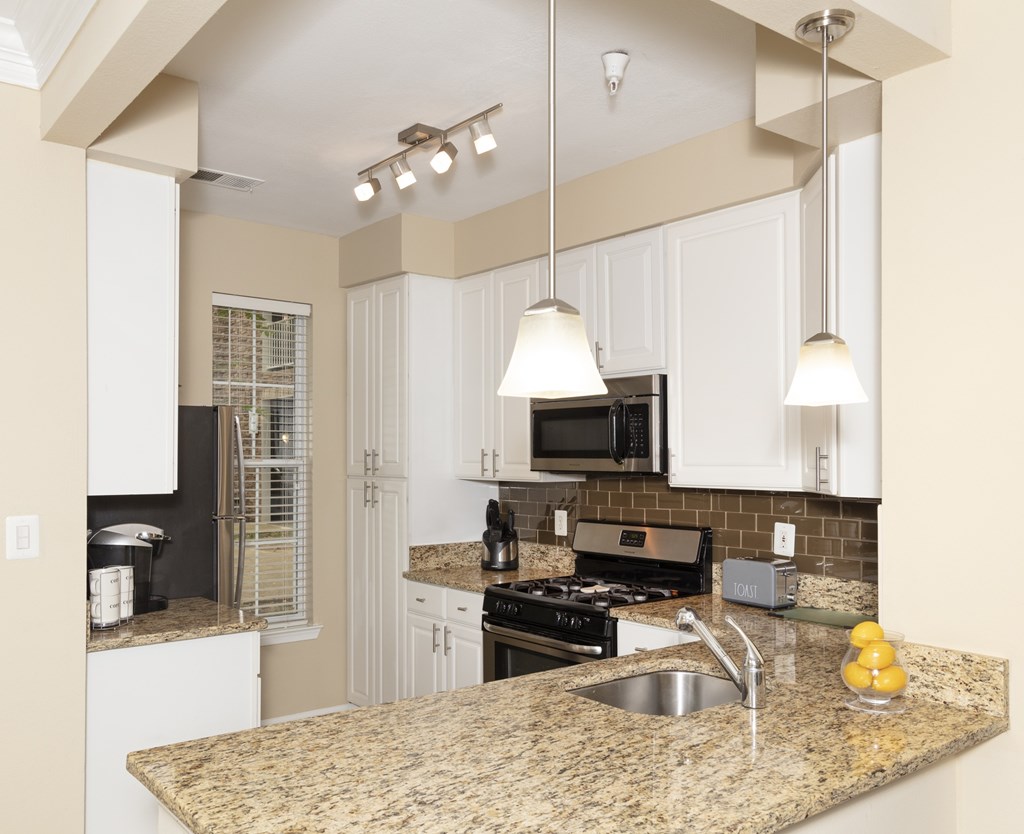 A kitchen with granite countertops and white cabinets.