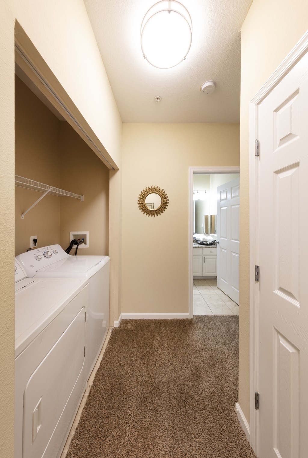 A white bedroom with a round mirror on the wall.