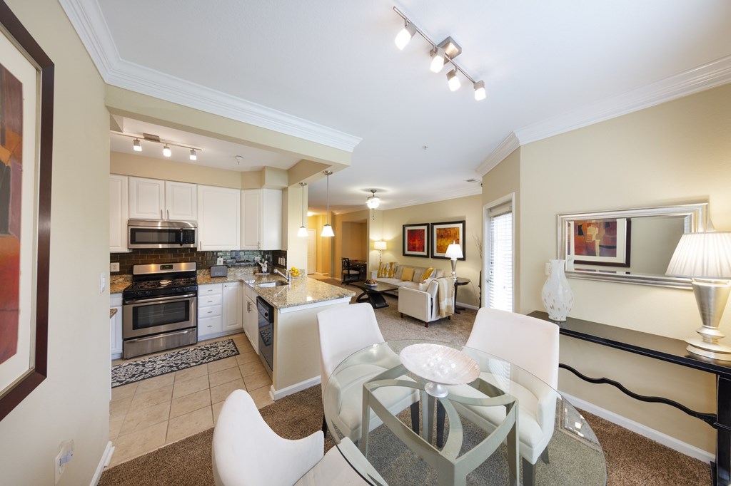 A modern kitchen with a glass dining table and chairs.