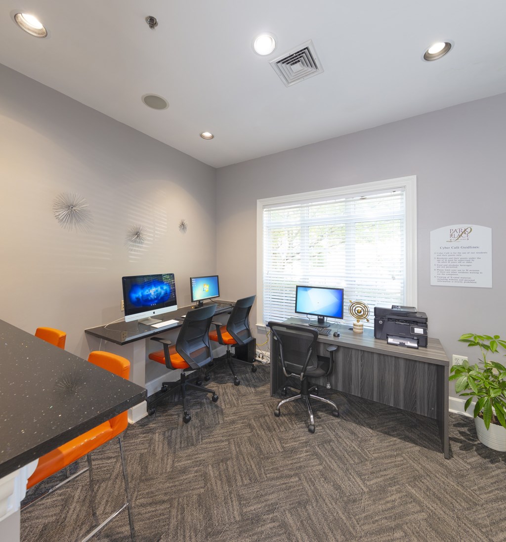A room with a desk, chairs, and computers.