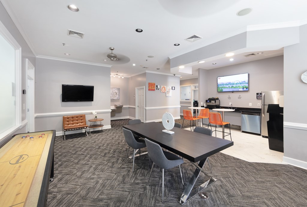 A conference room with a long table and chairs, a foosball table, and a television on the wall.