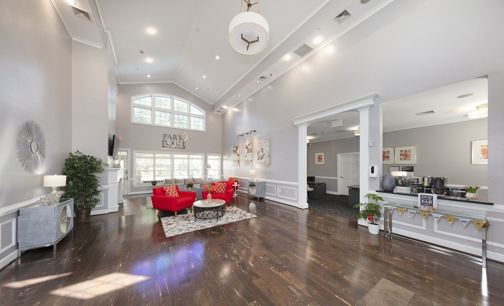 A spacious living room with a red couch and a wooden floor.