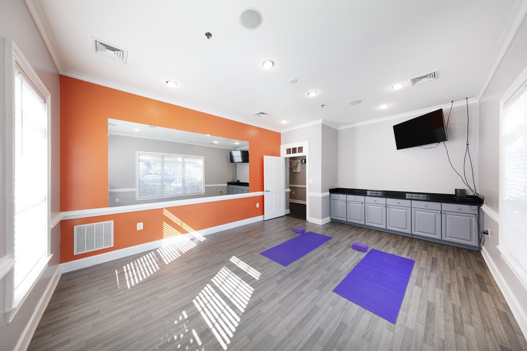 A room with orange walls and a grey floor has a purple mat on it.