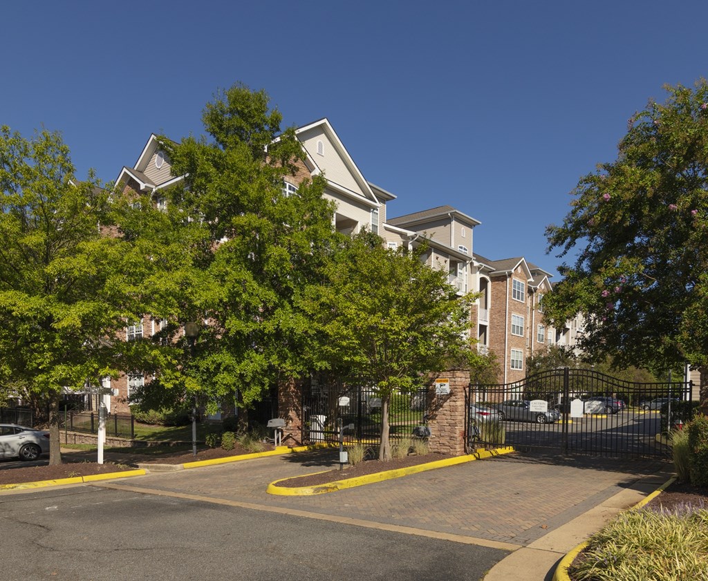 A large building with a gated entrance and a parking lot in front.