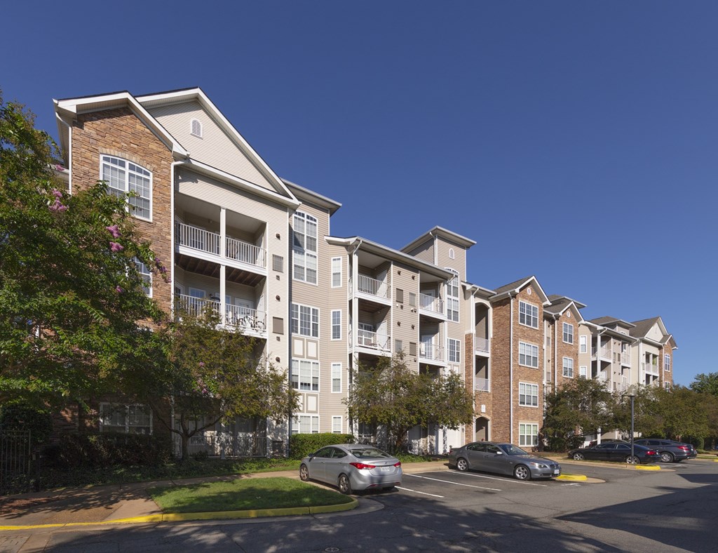 A large apartment complex with a parking lot in front.