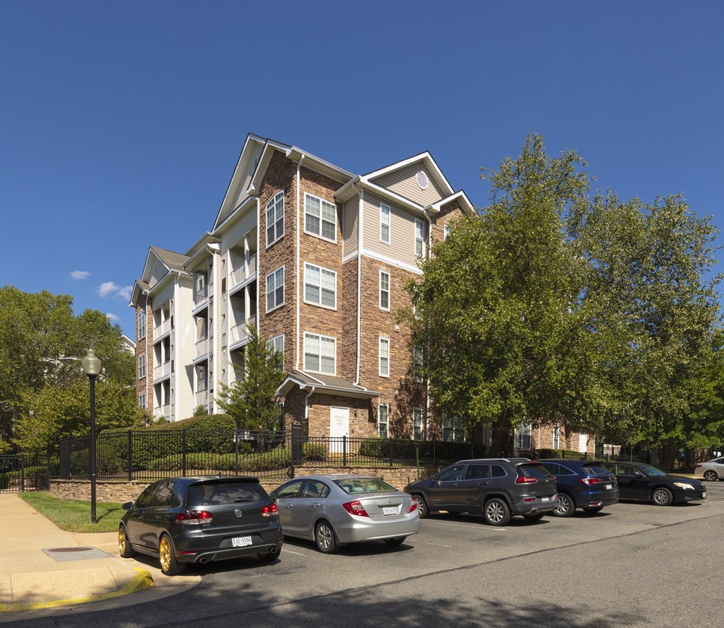 A black car is parked in front of a multi-story building.