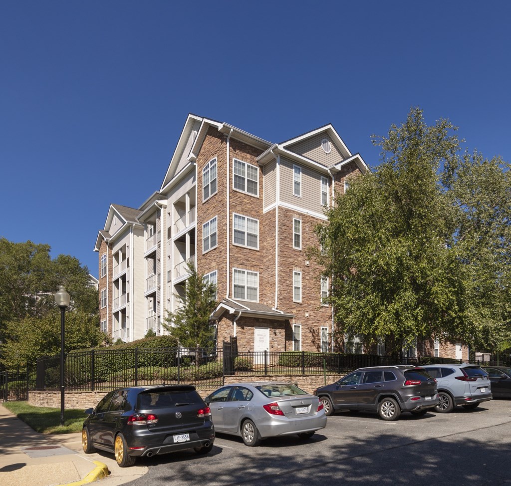 A black car is parked in front of a brick building.