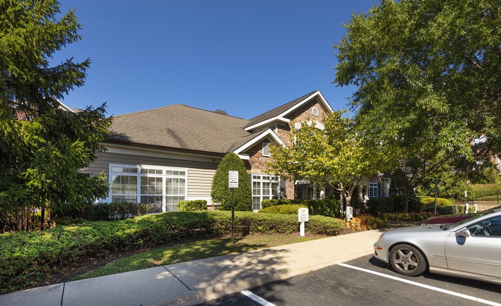 A silver car is parked on the side of a road in front of a house.