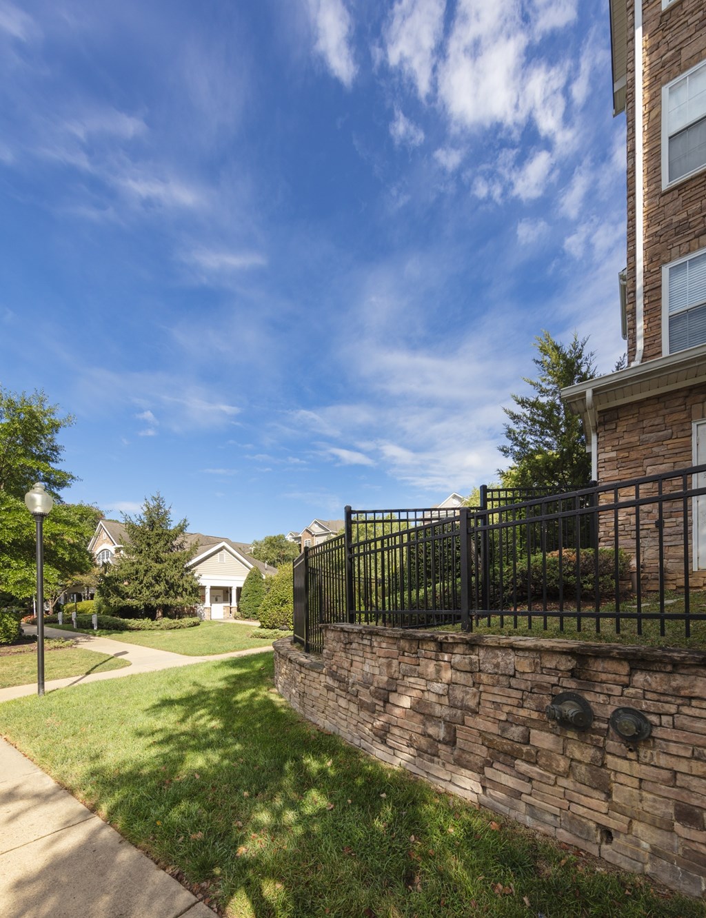 A house with a black fence and a stone wall.