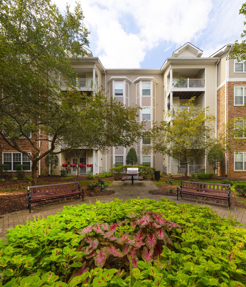 A large building with a balcony and a garden in front.