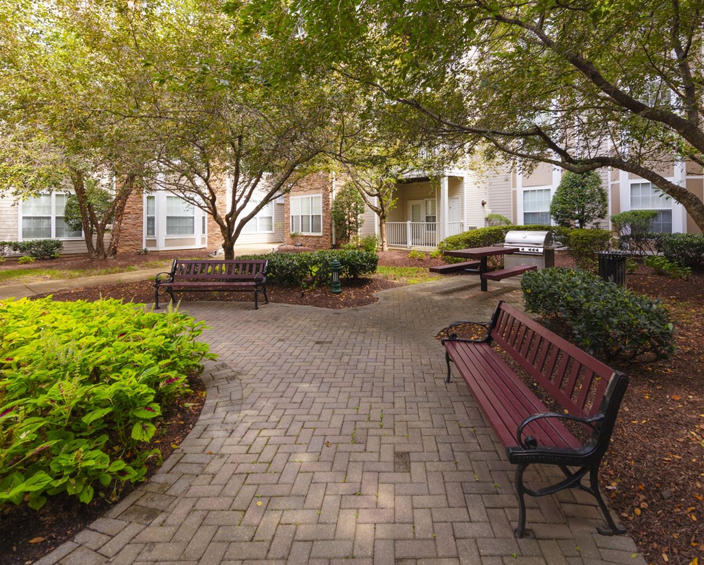 A park with benches and trees in front of apartment buildings.