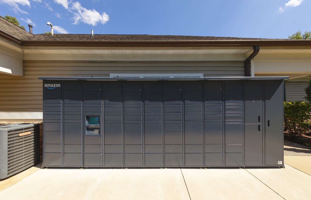 A large grey Amazon storage unit is in front of a house.