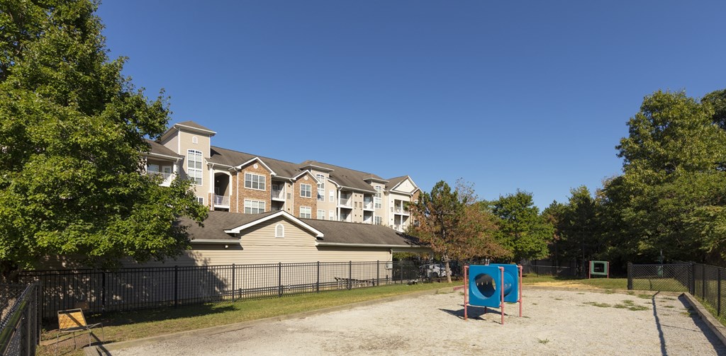 A playground with a slide is in front of a large building.