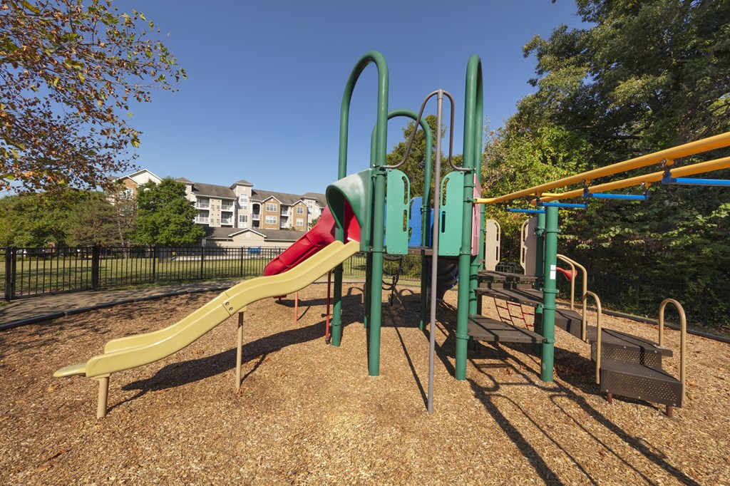 A playground with a yellow slide and green monkey bars.