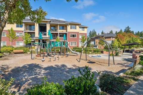 a playground with a swing set in front of an apartment building