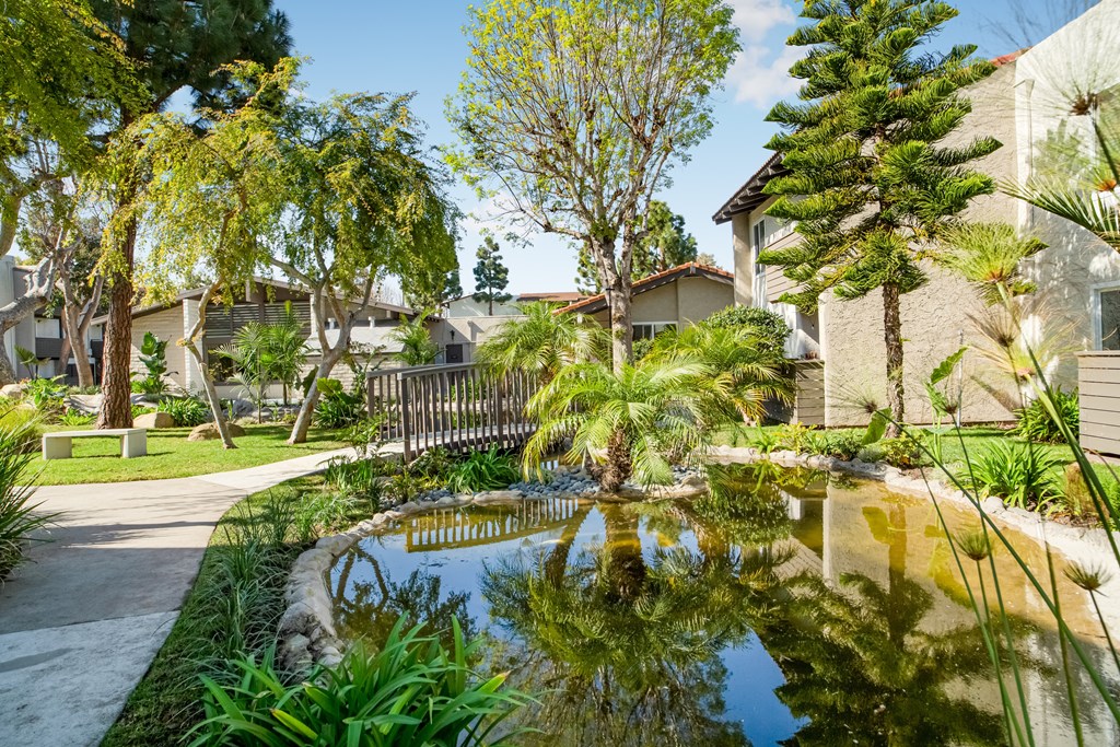A pond in a garden with a house in the background.