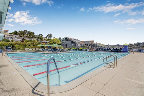 A large outdoor swimming pool with a blue sky and clouds in the background.