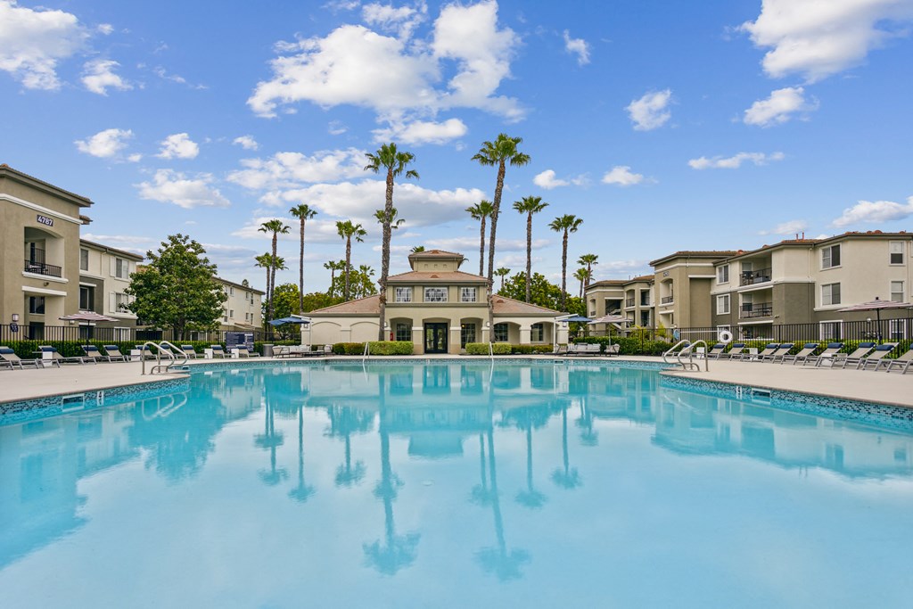 a large swimming pool with apartment buildings and palm trees